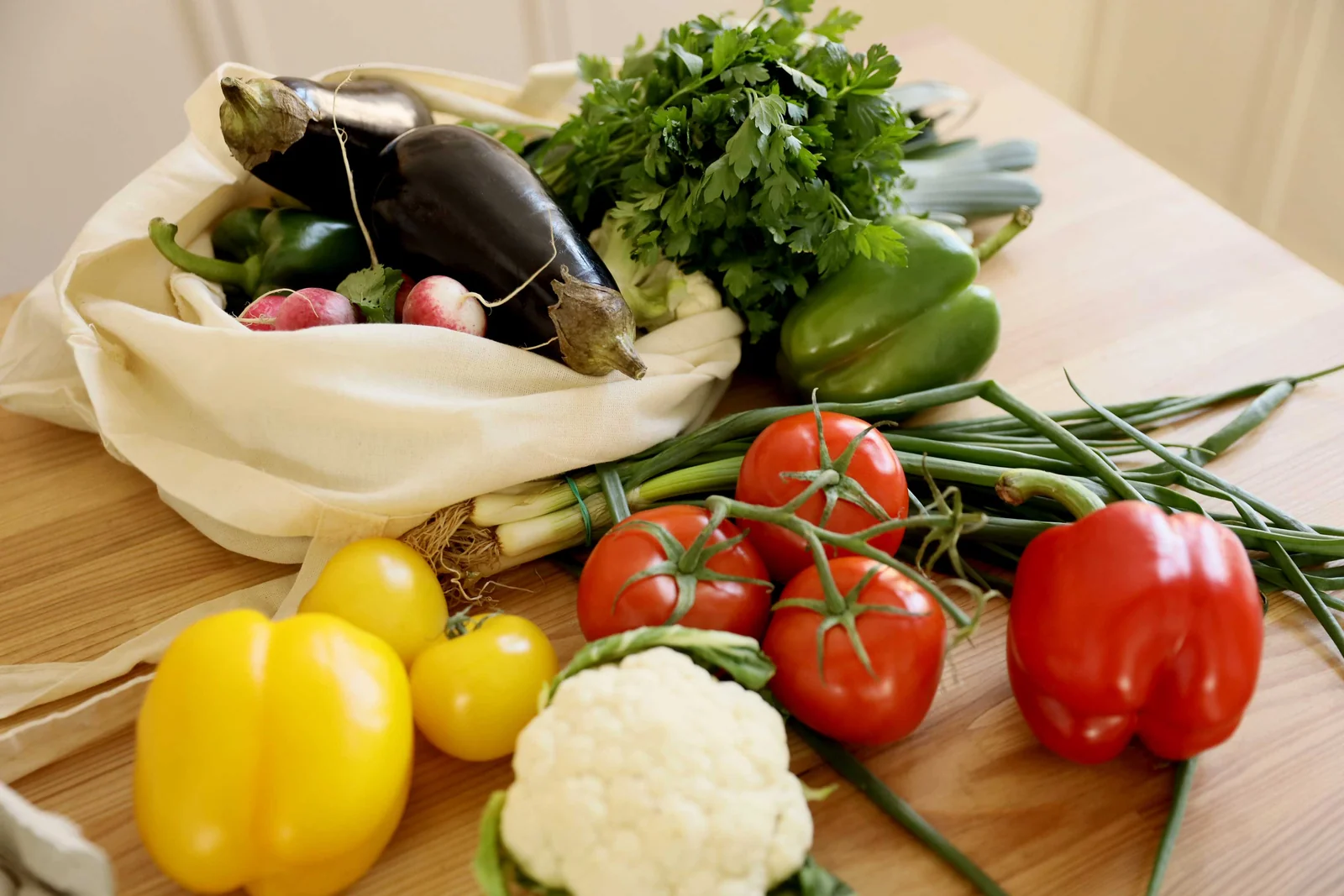 Légumes frais sur une table en bois, certains dans un sac en toile